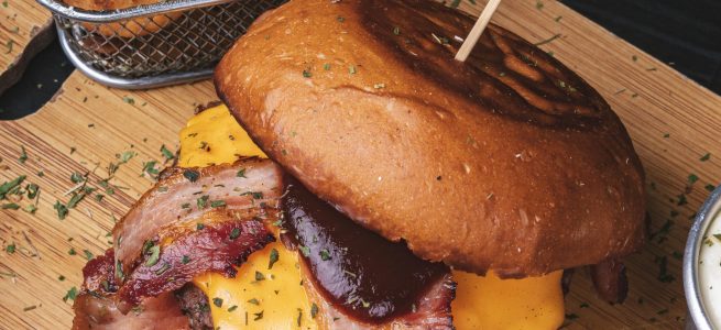 Hambúrguer com cheddar, bacon, molho barbecue, rúcula, maionese e porção de cebola empanada